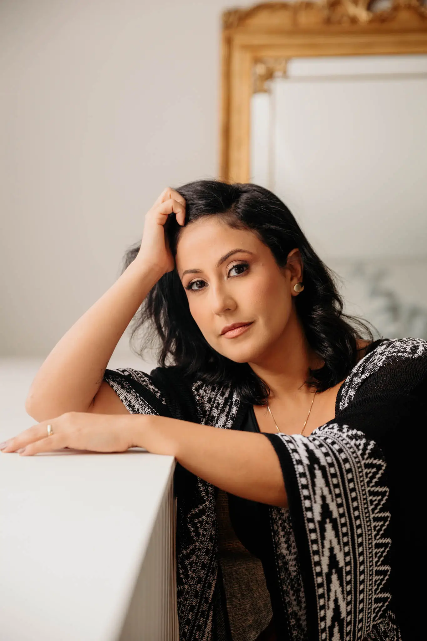 Alejandra Leão apoiada em uma bancada clara, olhando para a câmera